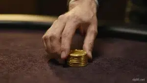 一隻手把一小疊金色籌碼推過深棕色絨布桌面,前方是空曠的絨布,暖金聚光燈